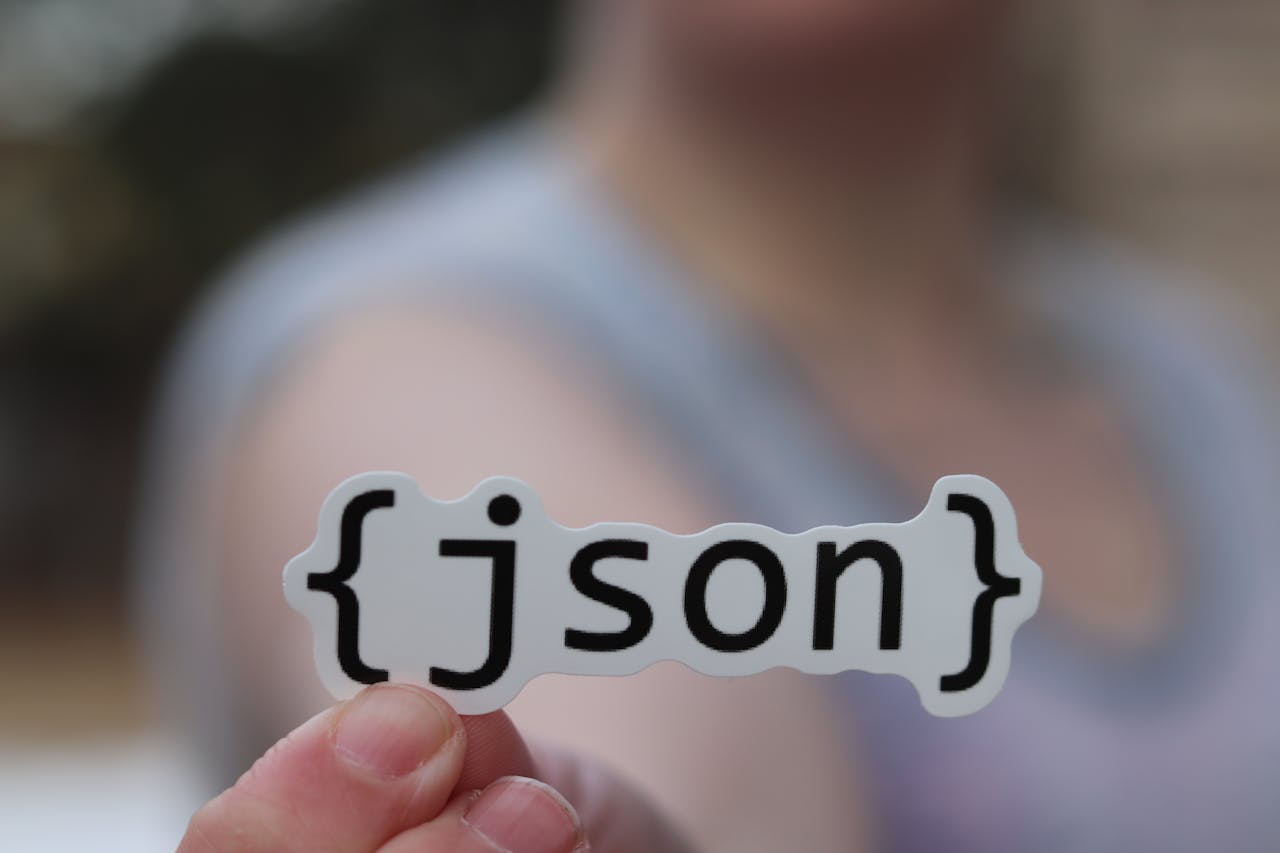 Services A hand holding a JSON text sticker, symbolic for software development.
